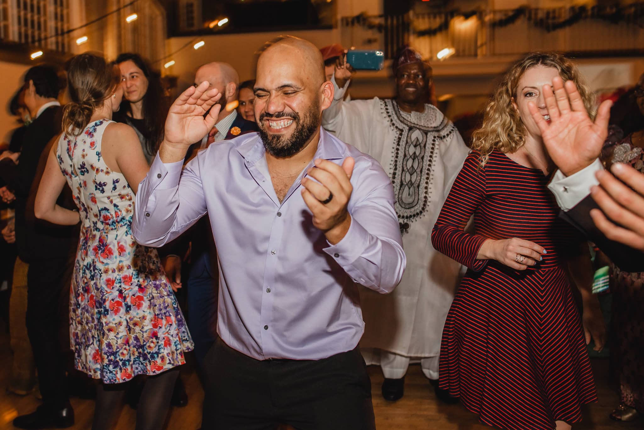 Guests danced joyfully at the wedding at the Evergreen, including a man in a lavender shirt and others in vibrant outfits.