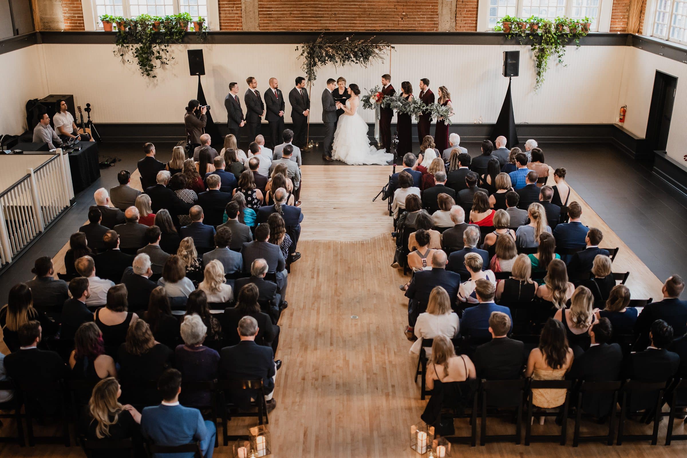 Wide shot of a wedding ceremony at The Evergreen, a Portland wedding venue, where guests are seated and the wedding party stands elegantly at the front.