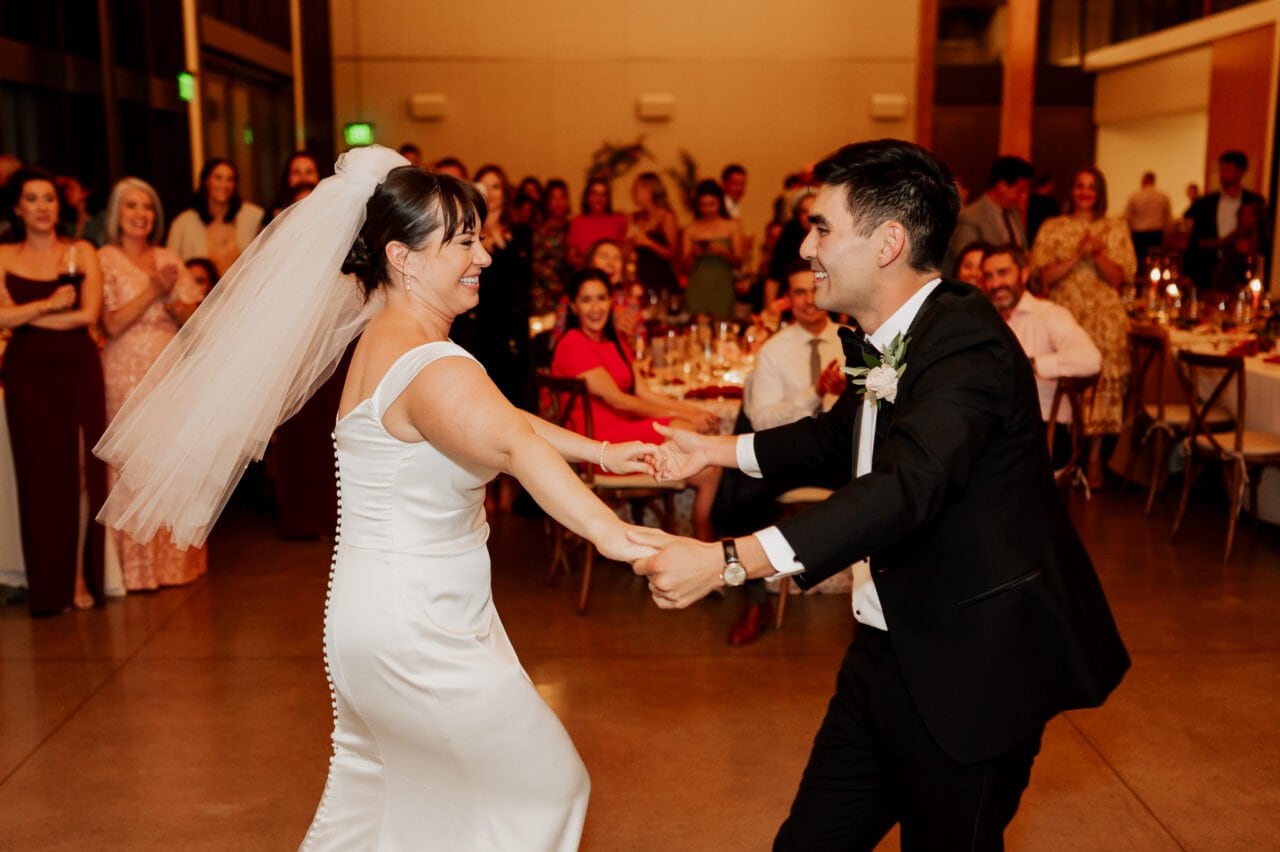 At the Amaterra Winery, the bride and groom joyfully dance at their wedding reception, surrounded by smiling guests in a scene perfect for capturing unforgettable wedding photos.