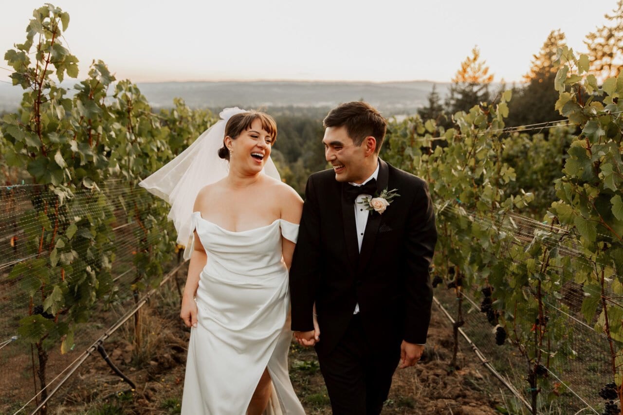 Bride and groom laughing as they walk through the scenic vineyards, capturing beautiful Amaterra Winery wedding photos.