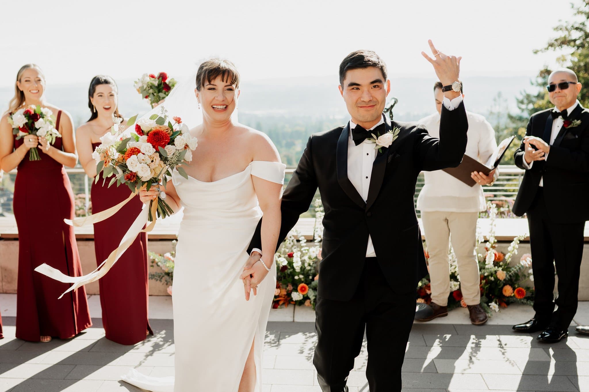 The bride and groom walked joyfully at their Amaterra Winery wedding, surrounded by their cheerful bridal party and guests in a picturesque outdoor setting.