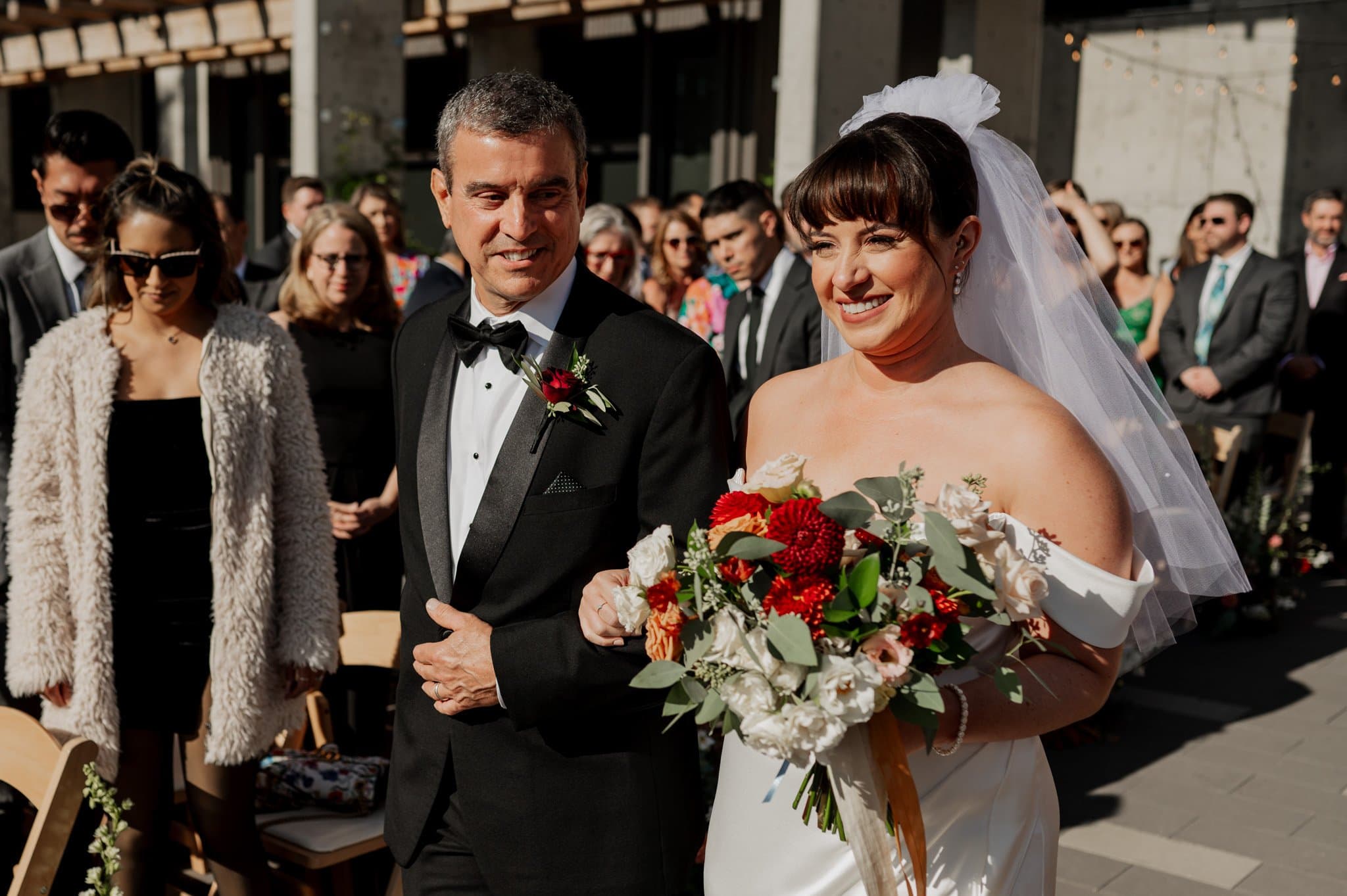 A bride and a man walk down the aisle at an outdoor wedding, surrounded by guests, their moment beautifully captured in Amaterra Winery wedding photos.