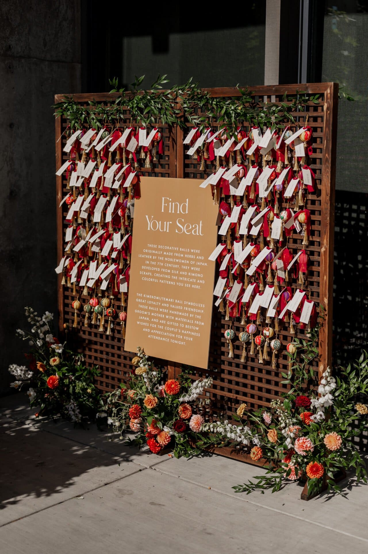 A wedding seating chart with red ribbons, name tags, and floral decorations adorns a wooden board, perfectly capturing the elegance of Amaterra Winery wedding photos.