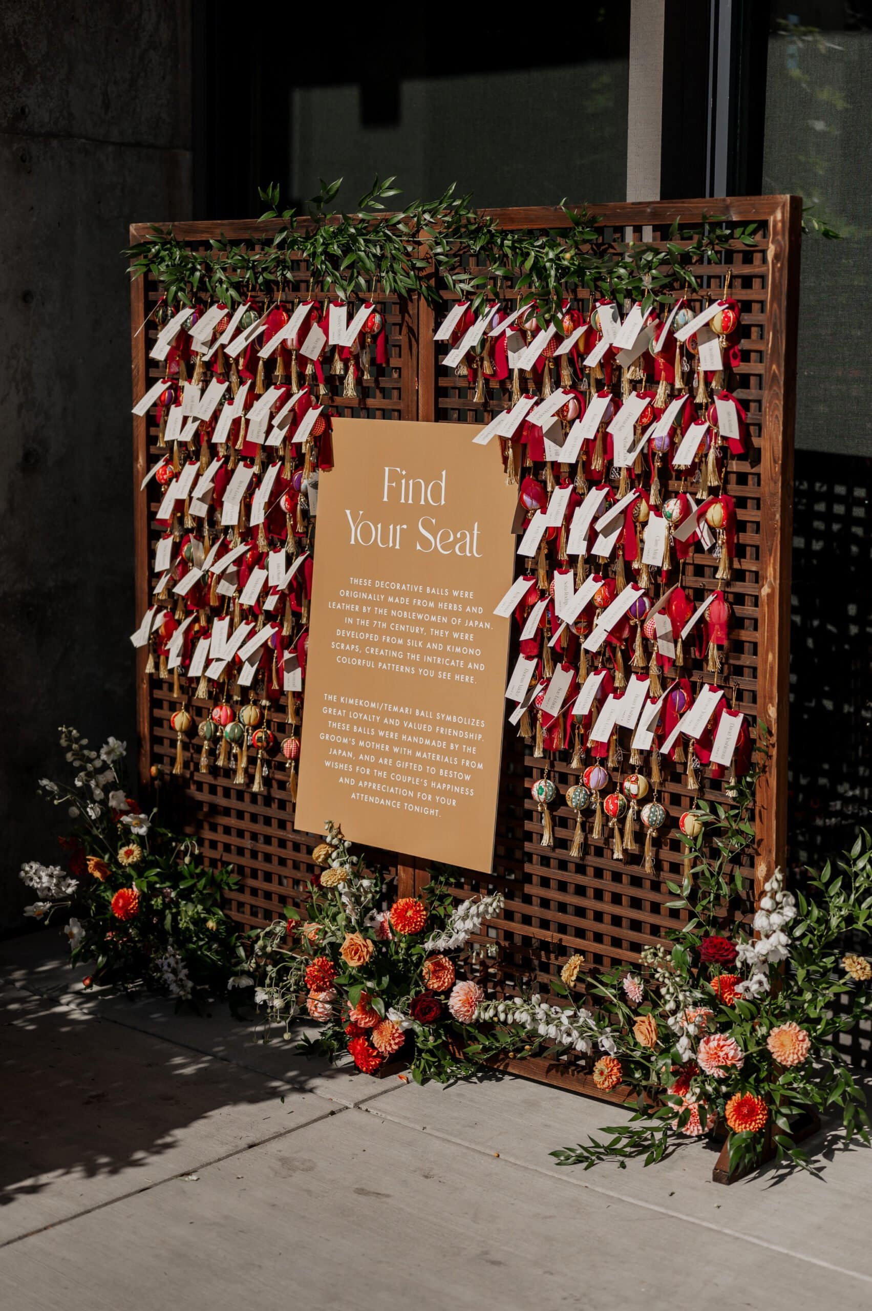 A wedding seating chart with red ribbons, name tags, and floral decorations adorns a wooden board, perfectly capturing the elegance of Amaterra Winery wedding photos.