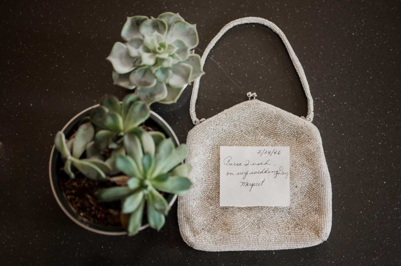 A succulent plant sits beside a beaded purse with a note that reads, Purse I used on my wedding day, 2/14/66. Its reminiscent of getting ready at The Heathman Hotel for an Amaterra Winery celebration.