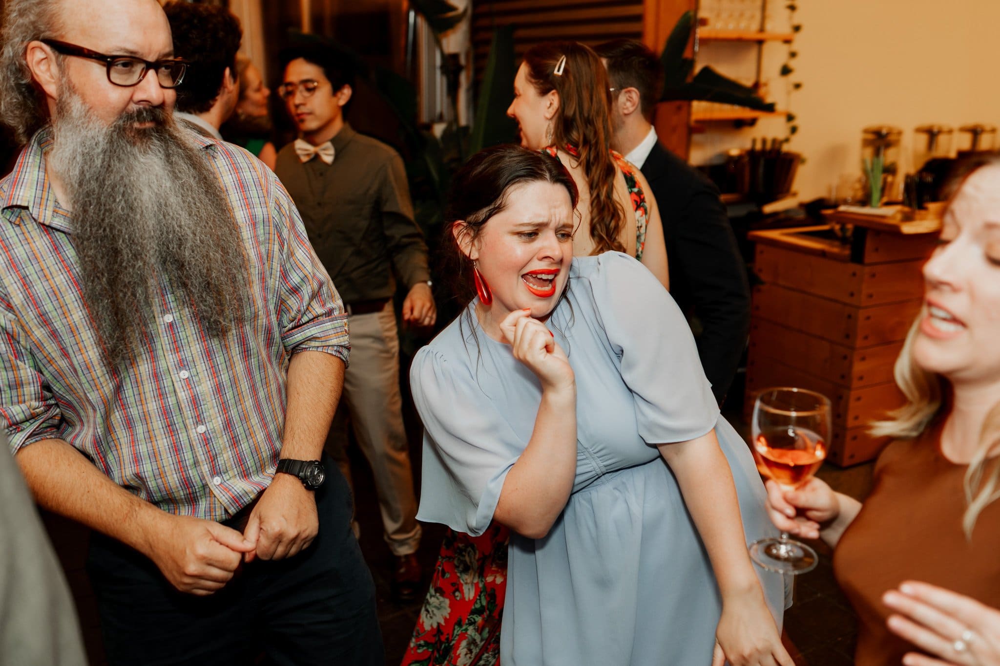 A joyful group of people dancing indoors at a social gathering, celebrating under the warm lights as if posing for wedding photos at Blockhouse.