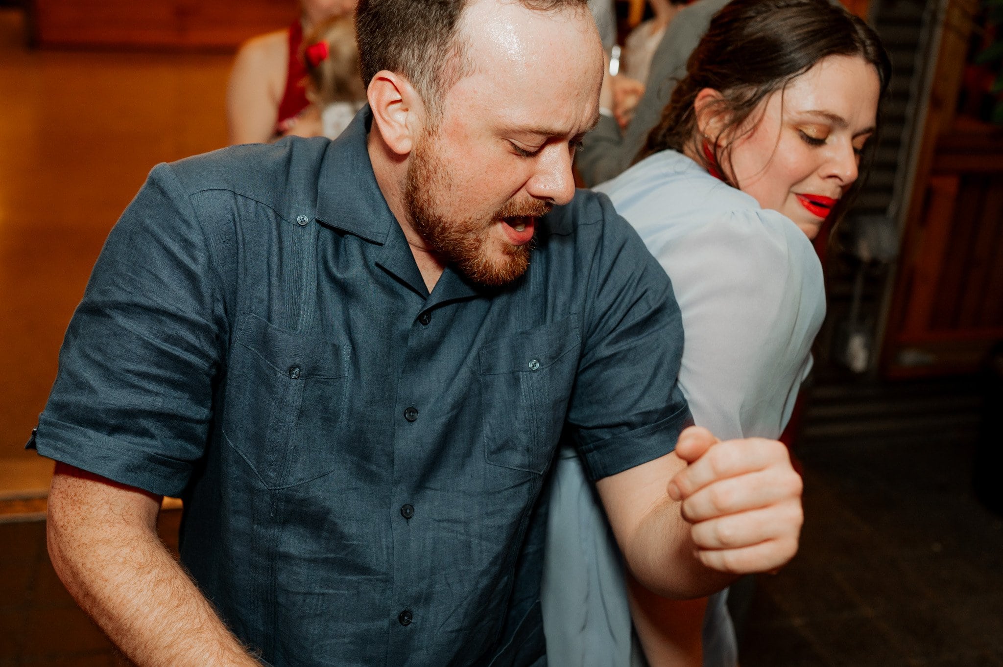 A man and woman energetically dancing together at an indoor event, capturing the lively spirit of wedding photos at Blockhouse.