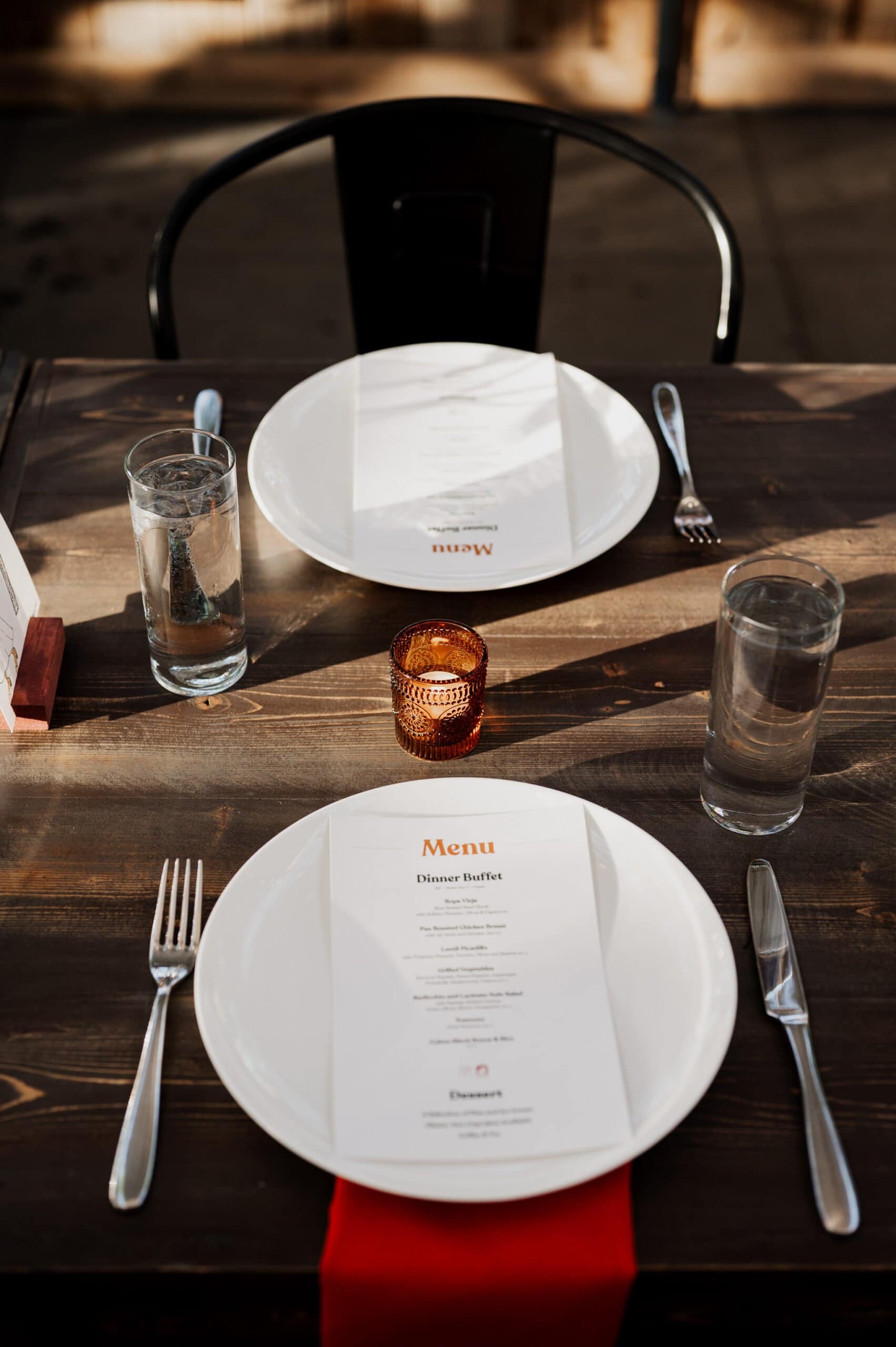 The table for two is adorned with menus, plates, forks, knives, and water glasses surrounding a central candle on the wooden surface. The elegant setting evokes an intimate atmosphere perfect for capturing wedding photos at Blockhouse.