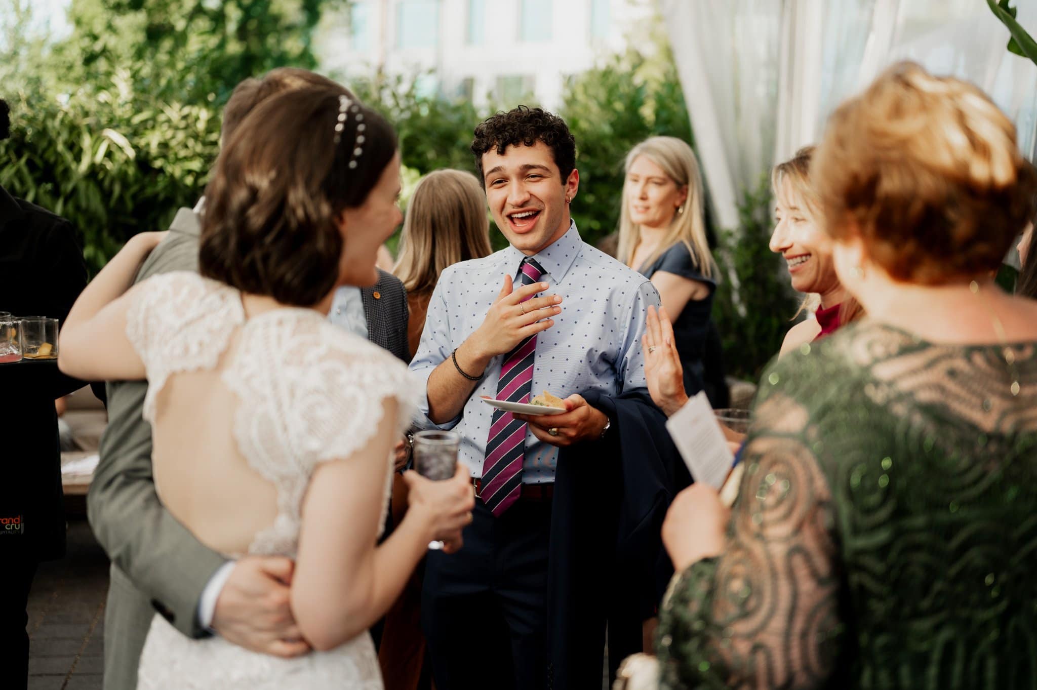 The groom shares a laugh with guests during an outdoor wedding reception, as the perfect backdrop for wedding photos at Blockhouse.
