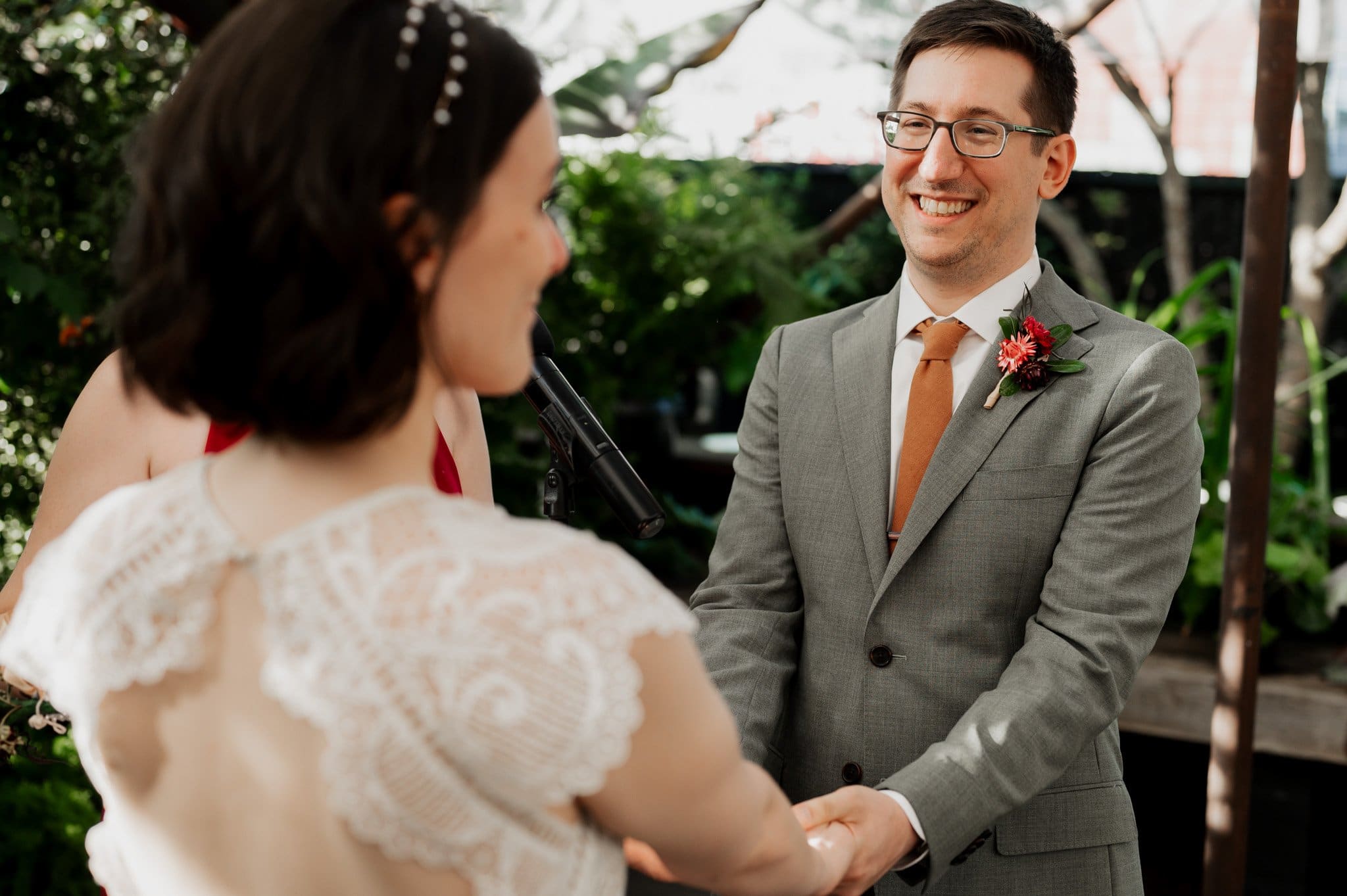 The bride and groom share a joyful moment holding hands and smiling during their outdoor wedding ceremony, perfect for capturing stunning wedding photos at Blockhouse.