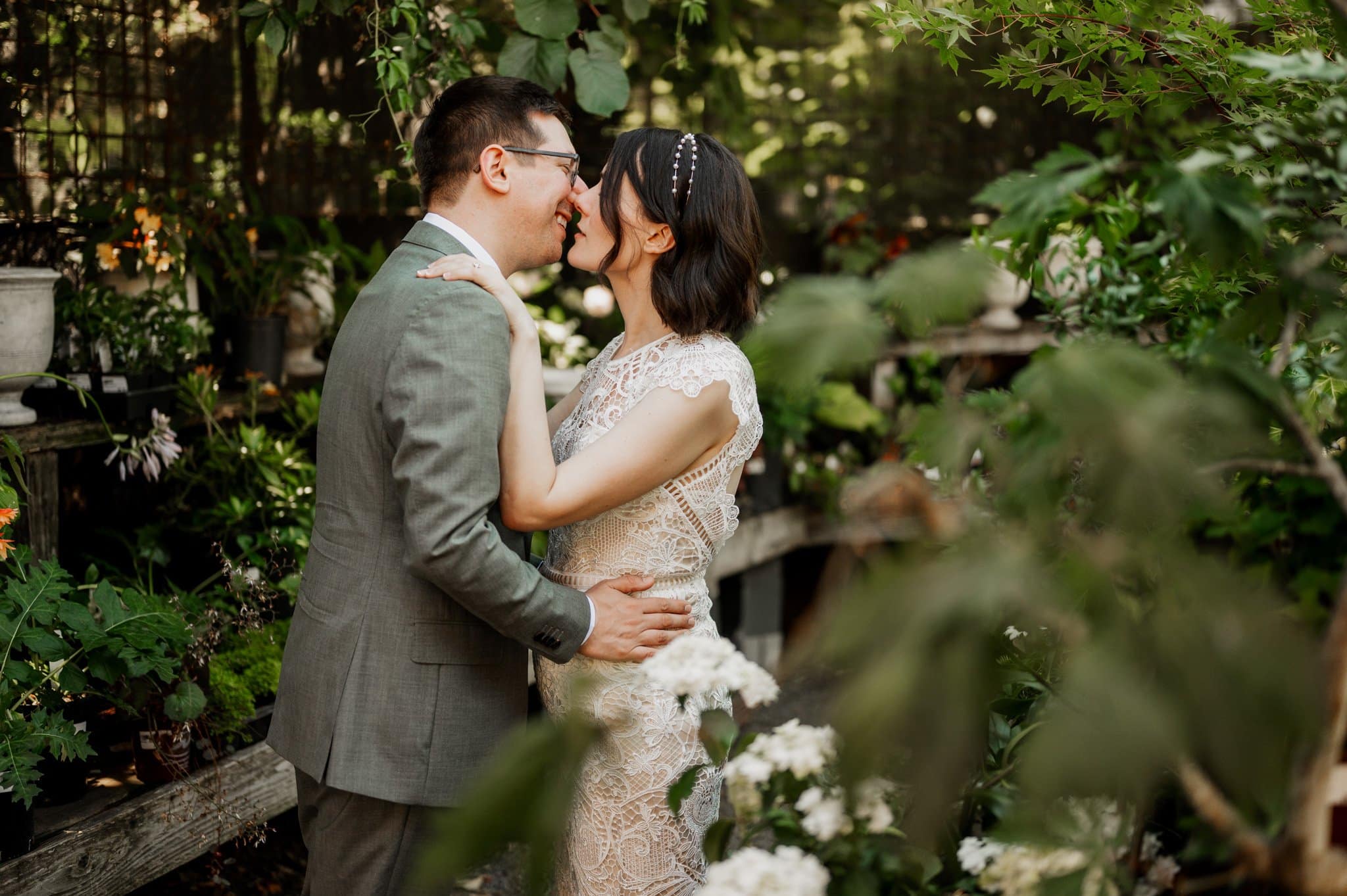 The couple in wedding attire embraces, sharing a joyful moment amid the lush garden setting, capturing a perfect scene for wedding photos at Blockhouse.