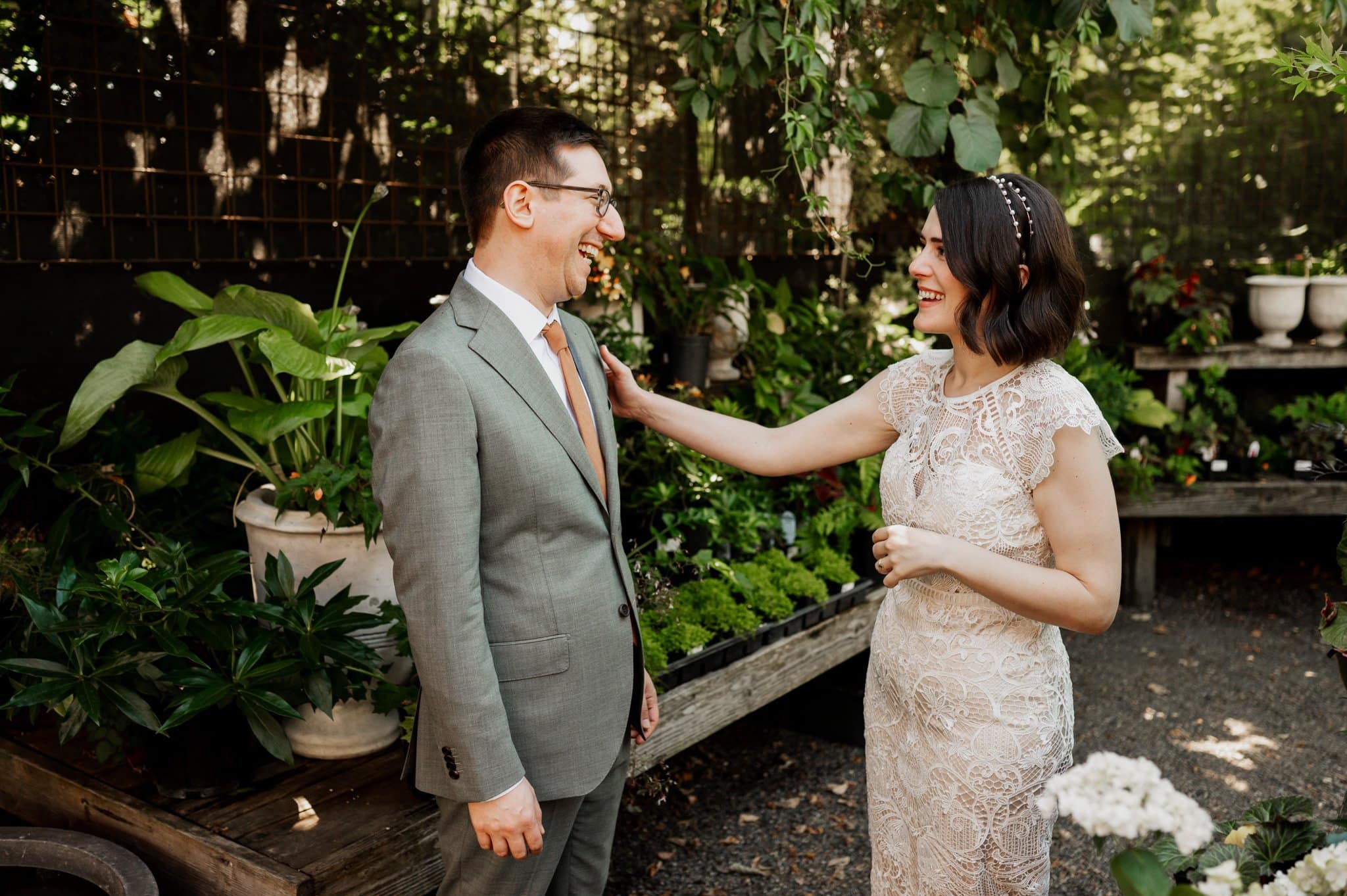 A couple smiling at each other in a garden, with the woman touching the mans shoulder, is captured in one of their beautiful wedding photos at Blockhouse.