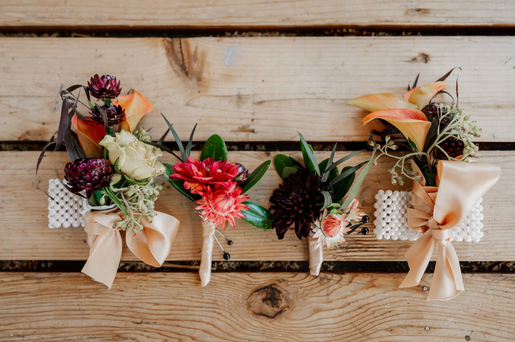 Four charming bouquets featuring pink, white, and orange flowers gracefully arranged on a wooden surface. Perfect for adding a pop of color to any setting, these blooms offer a delightful touch during wedding photos at Blockhouse.