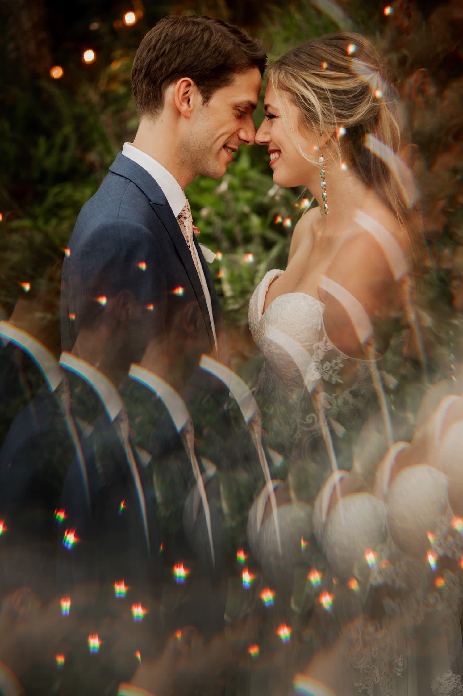A bride and groom stand closely at their Cape Horn Estate wedding, touching foreheads and smiling. They are surrounded by ethereal, refracted light effects in the foreground.