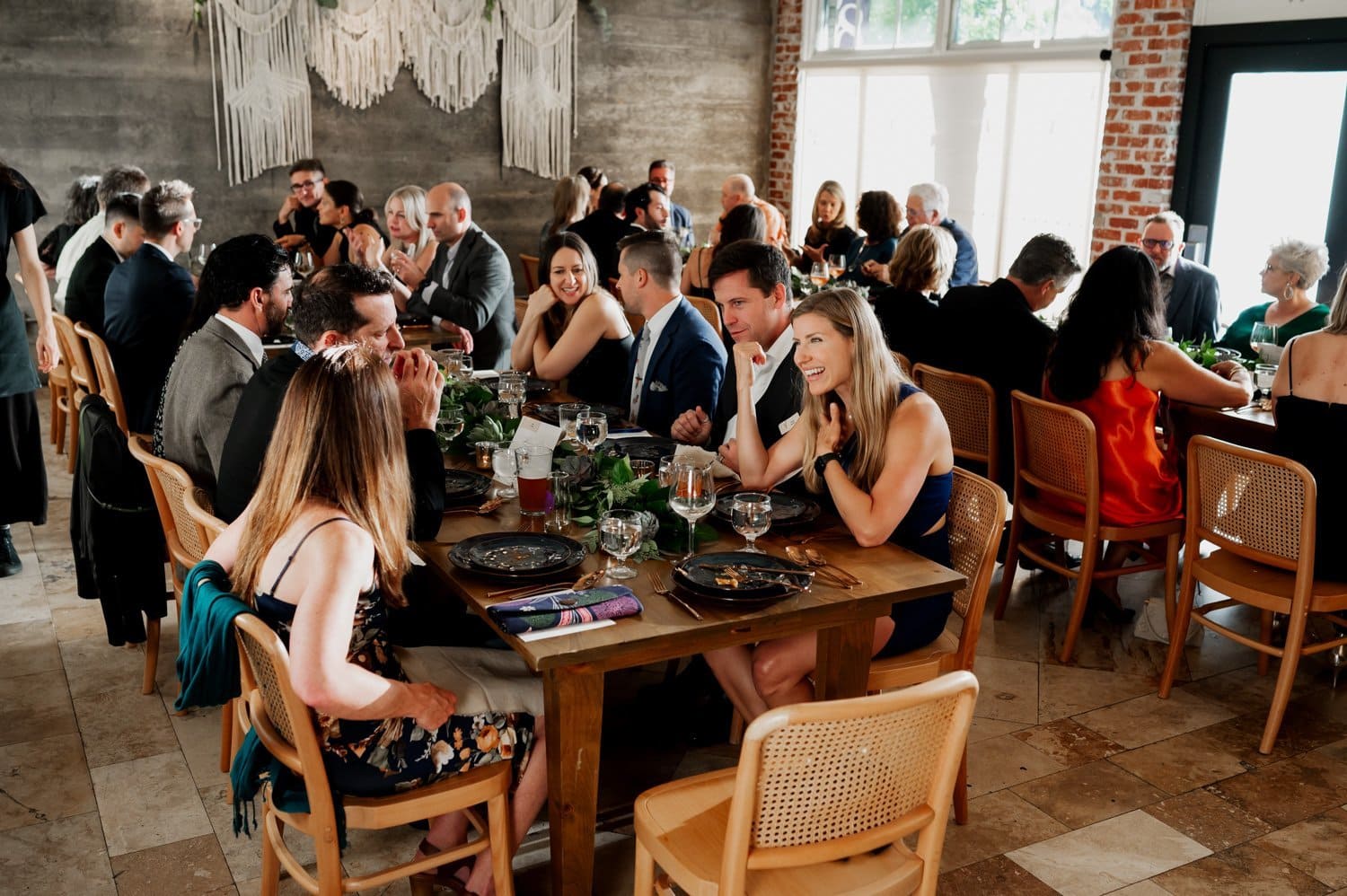 A wedding at Opal 28 with guests in formal attire seated at elegantly decorated tables. The room is warmly lit, and people are chatting and enjoying their meals in the charming dining space.