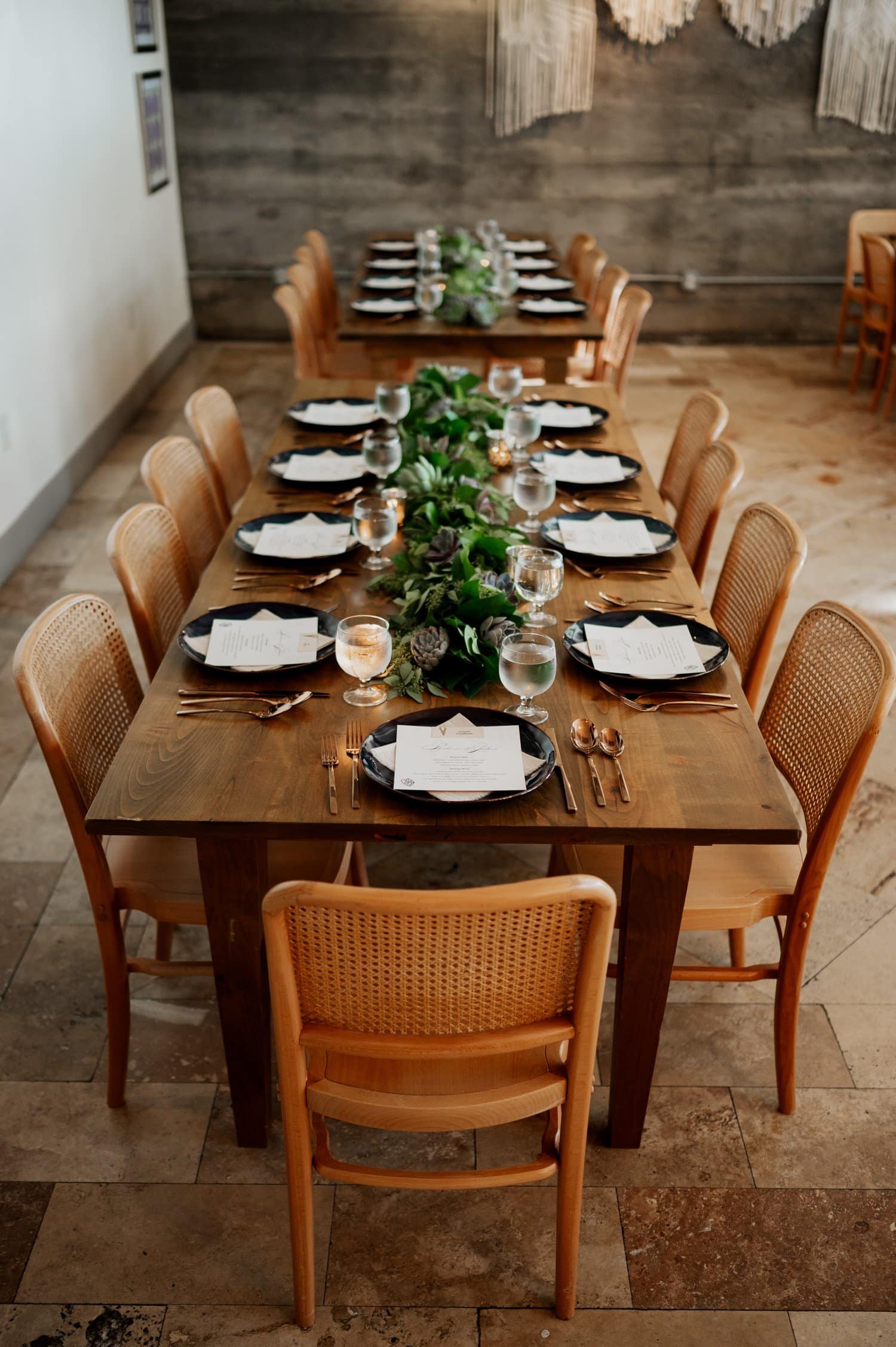 An elegantly set dining table for a formal event, featuring neatly arranged plates and glasses, complemented by a lush greenery centerpiece at Opal 28.
