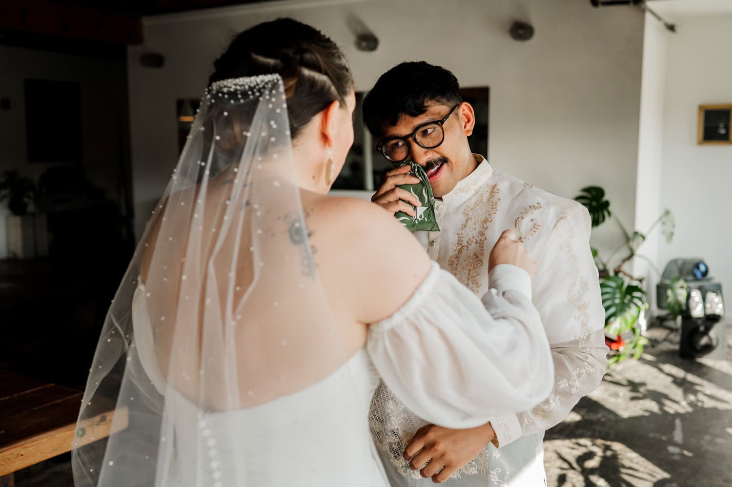 The groom playfully holds a cloth near his face, making the bride smile warmly at their wedding in Union/Pine.
