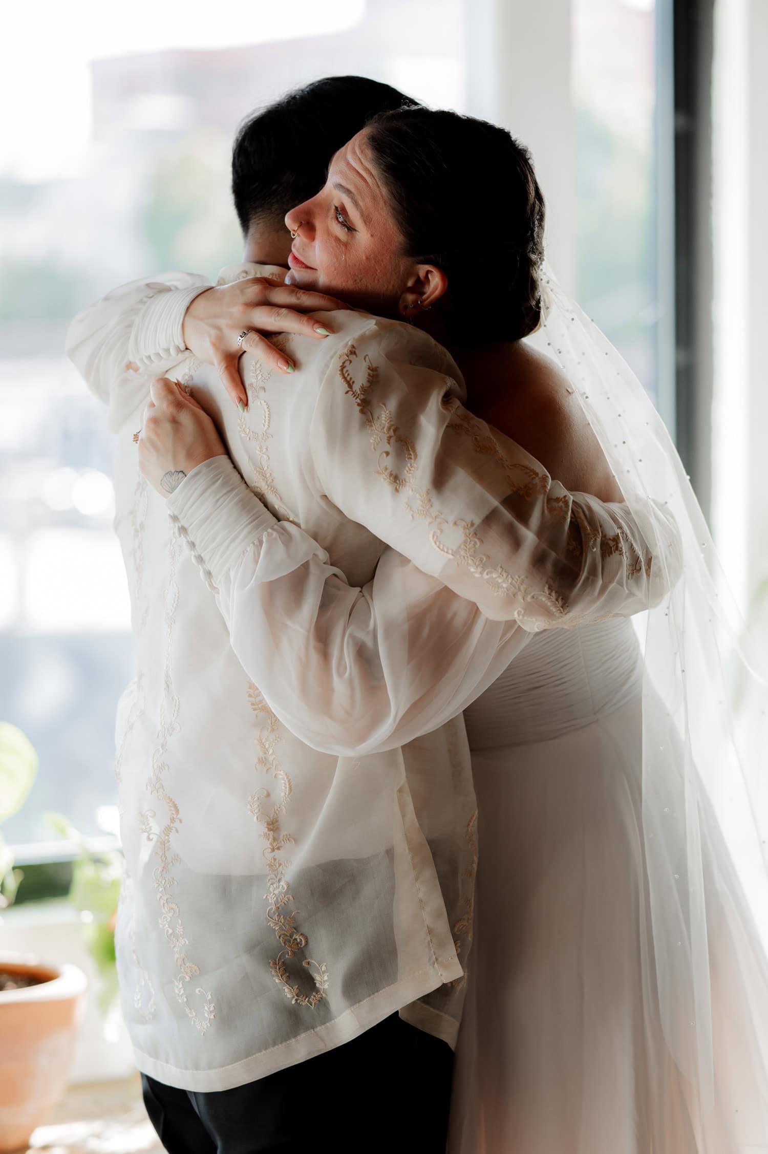 A bride and groom embrace by a sunlit window on their wedding day at Union/Pine.