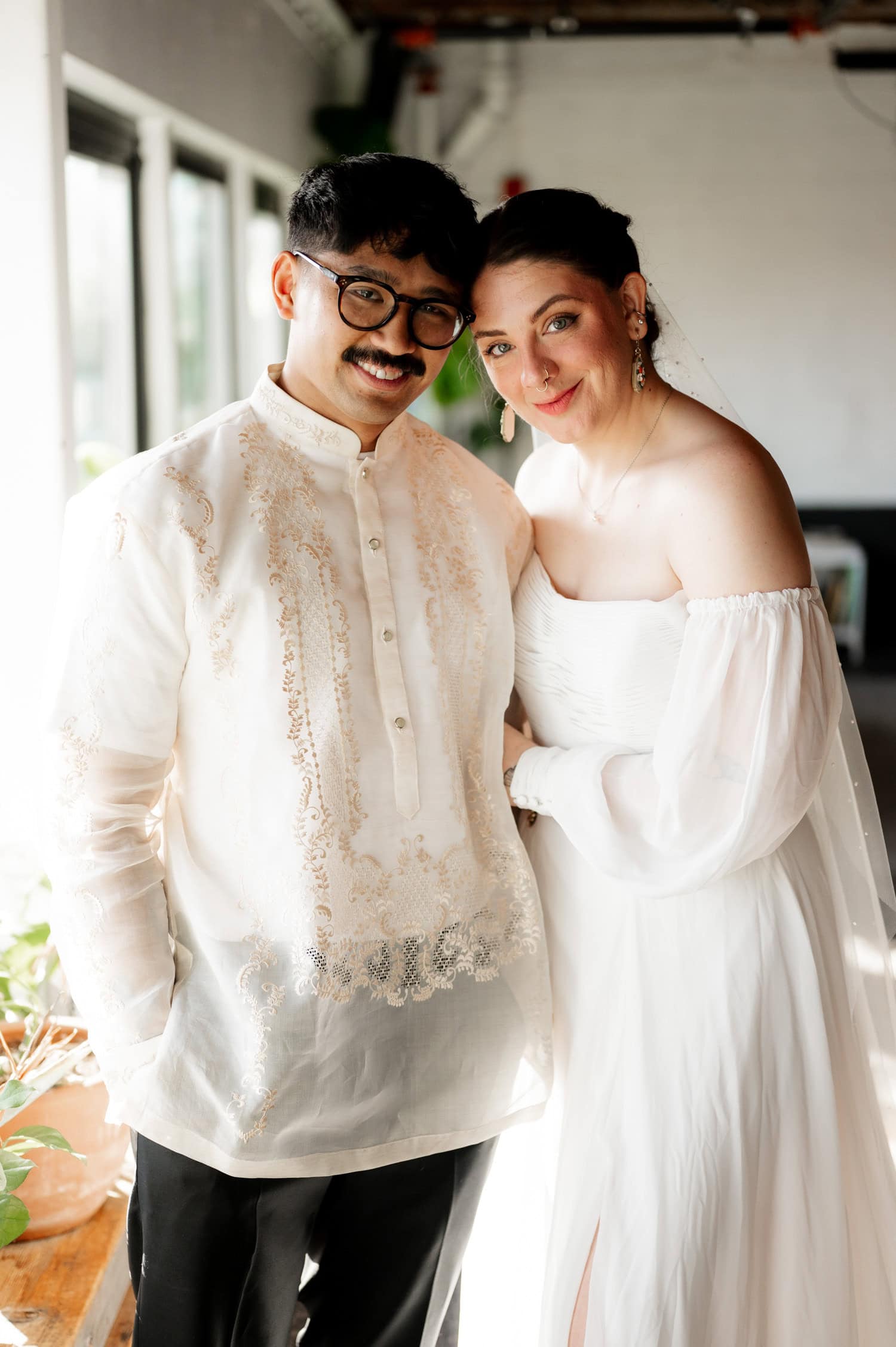 The couple smiles warmly, the man in a barong and the woman in an off-shoulder white dress, capturing a moment of joy at their wedding at Union/Pine.