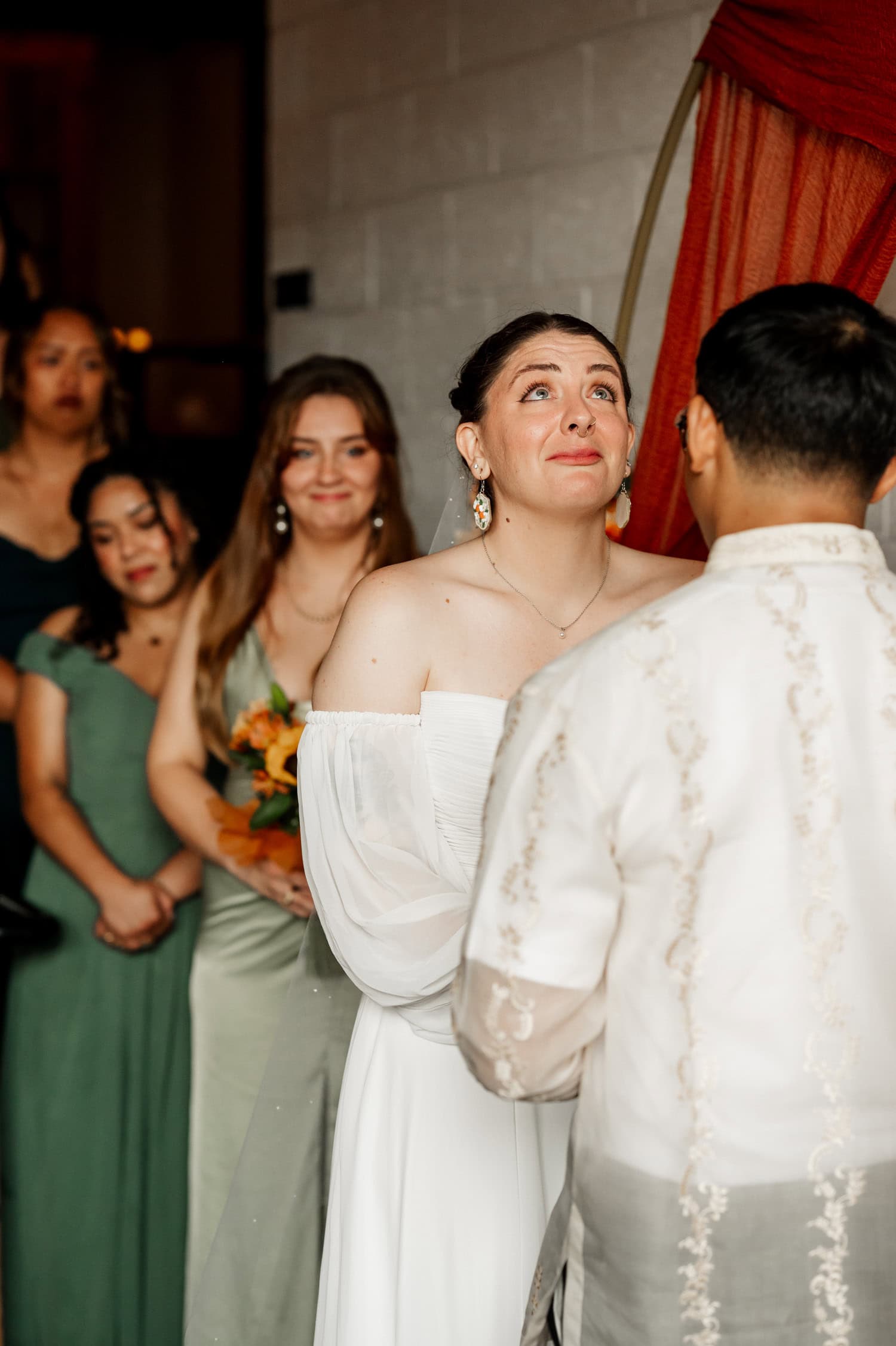 A bride smiling at her groom, surrounded by bridesmaids in green dresses, during a wedding ceremony at Union/Pine.