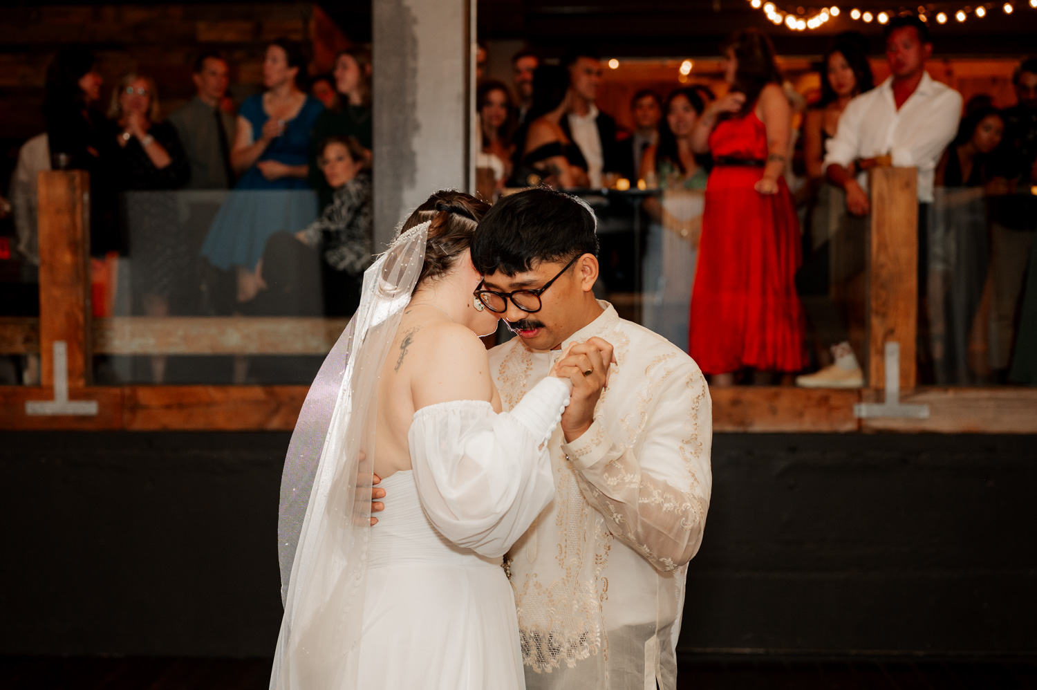 The bride and groom share a tender dance at their Union/Pine wedding reception, with guests watching in admiration.