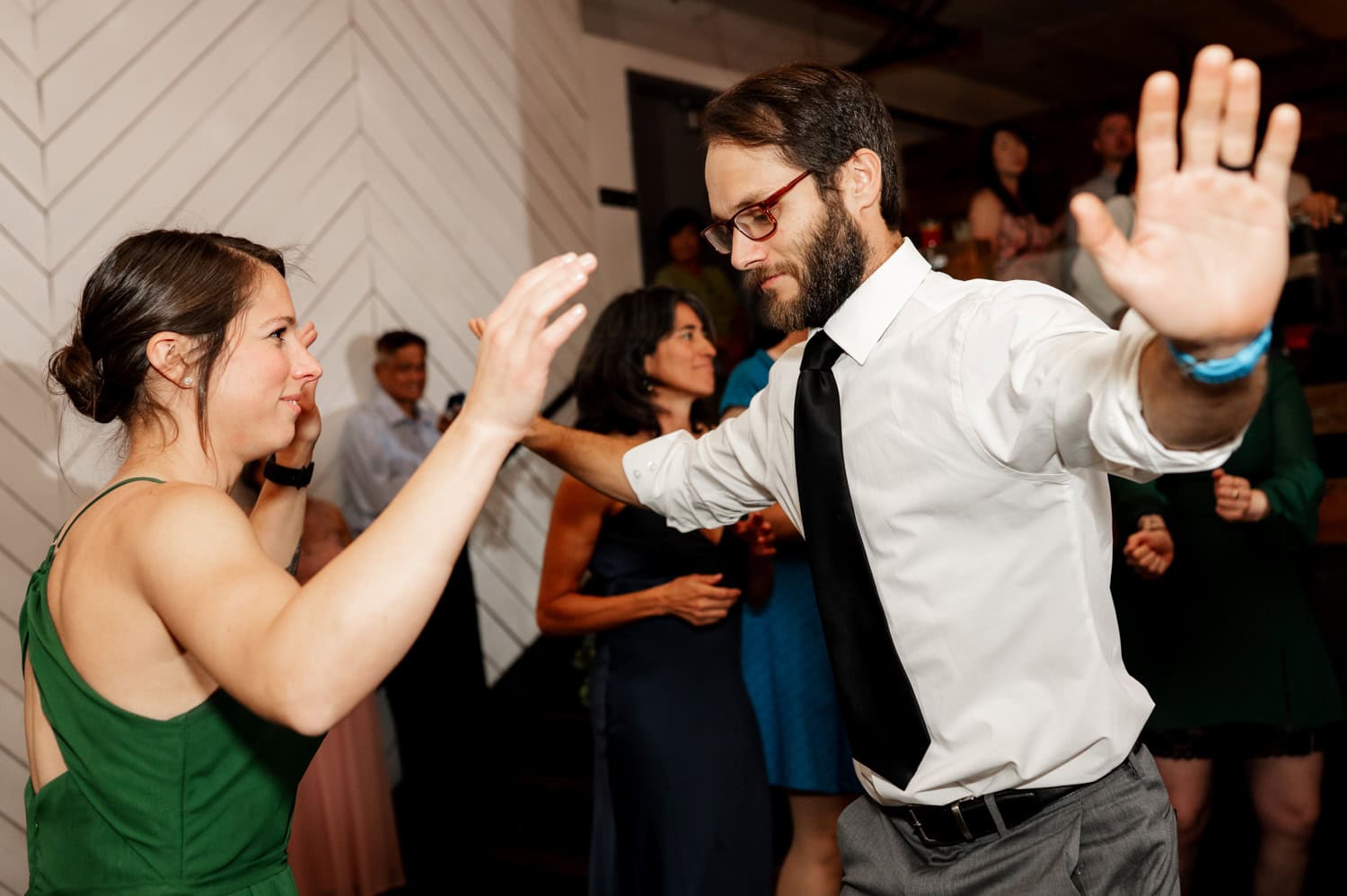 Two people dancing energetically at a wedding reception at Union/Pine with onlookers in the background.