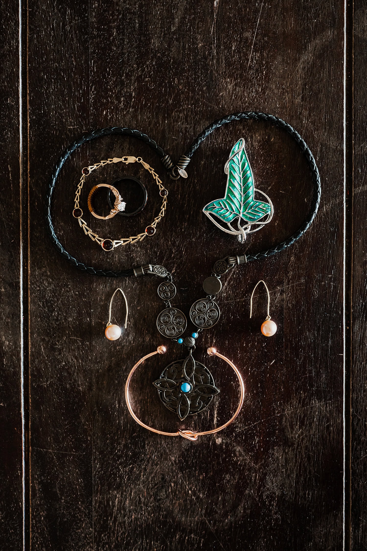 A collection of jewelry pieces arranged artistically on a dark wooden surface, including necklaces, earrings, and bracelets.