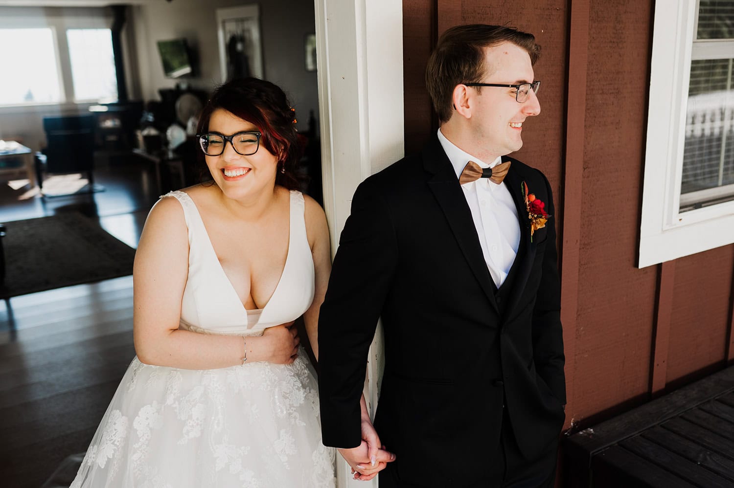 Bride and groom hold hands around a corner at Gorge Crest Vineyards, smiling in formal wedding attire.