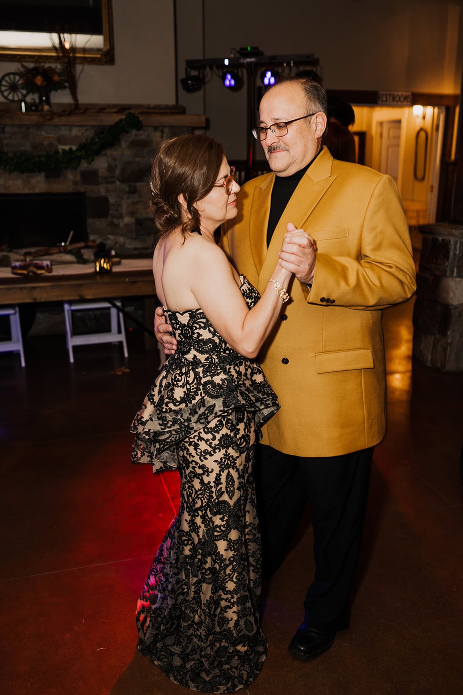 At the Gorge Crest Vineyards, a couple dances gracefully; the woman is wearing a lacy black dress and the man is dressed in a mustard-colored jacket.