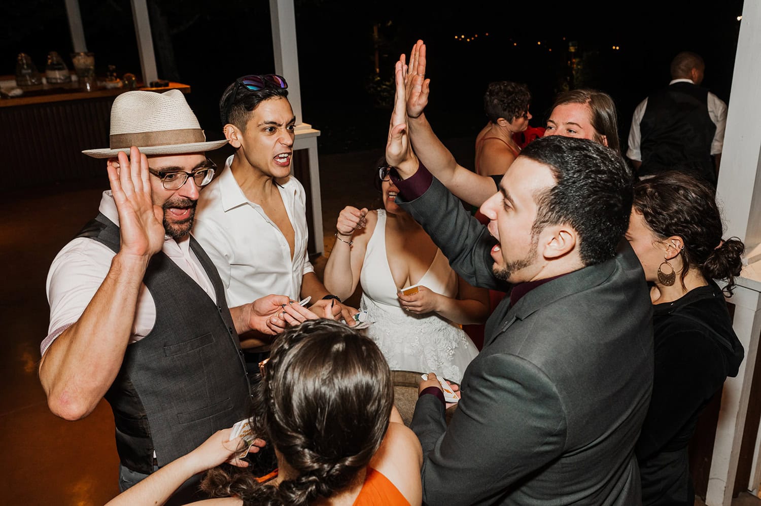 A group of people in formal attire celebrates indoors by high-fiving and smiling.
