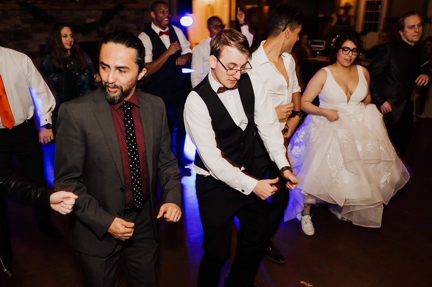 At a lively party at Gorge Crest Vineyards, a group of people dance energetically with the bride, who is wearing a stunning wedding dress, joining in the celebration.