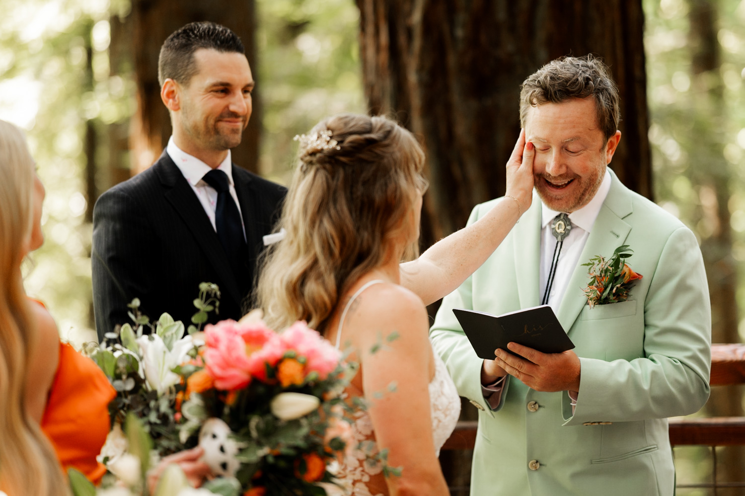 At their outdoor wedding ceremony on the Redwood Deck at Hoyt Arboretum, a bride wipes away her grooms tears while surrounded by towering trees.
