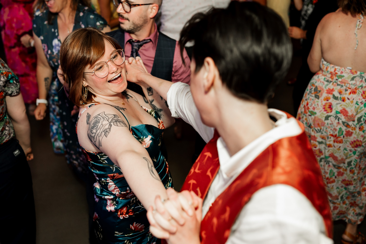 Two people dance joyfully at a lively wedding reception at Coopers Hall, surrounded by others celebrating.