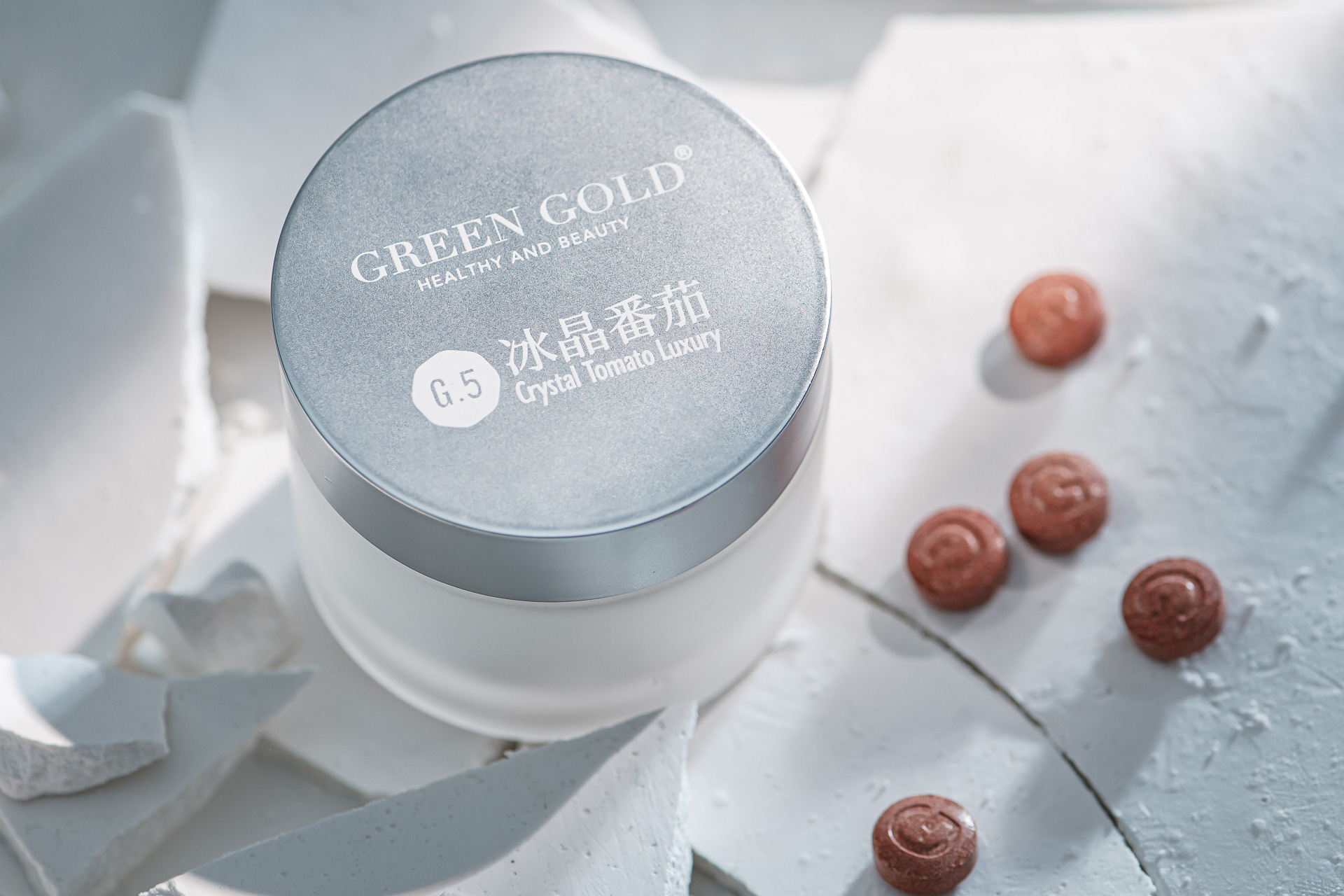 綠金 GreenGold 冰晶番茄精華產品，灰白色調容器搭配紅潤番茄球體，光影層次分明展現質感，台中品牌形象攝影由奇力克影像工作室 KYRIC STUDIO 專業打造。