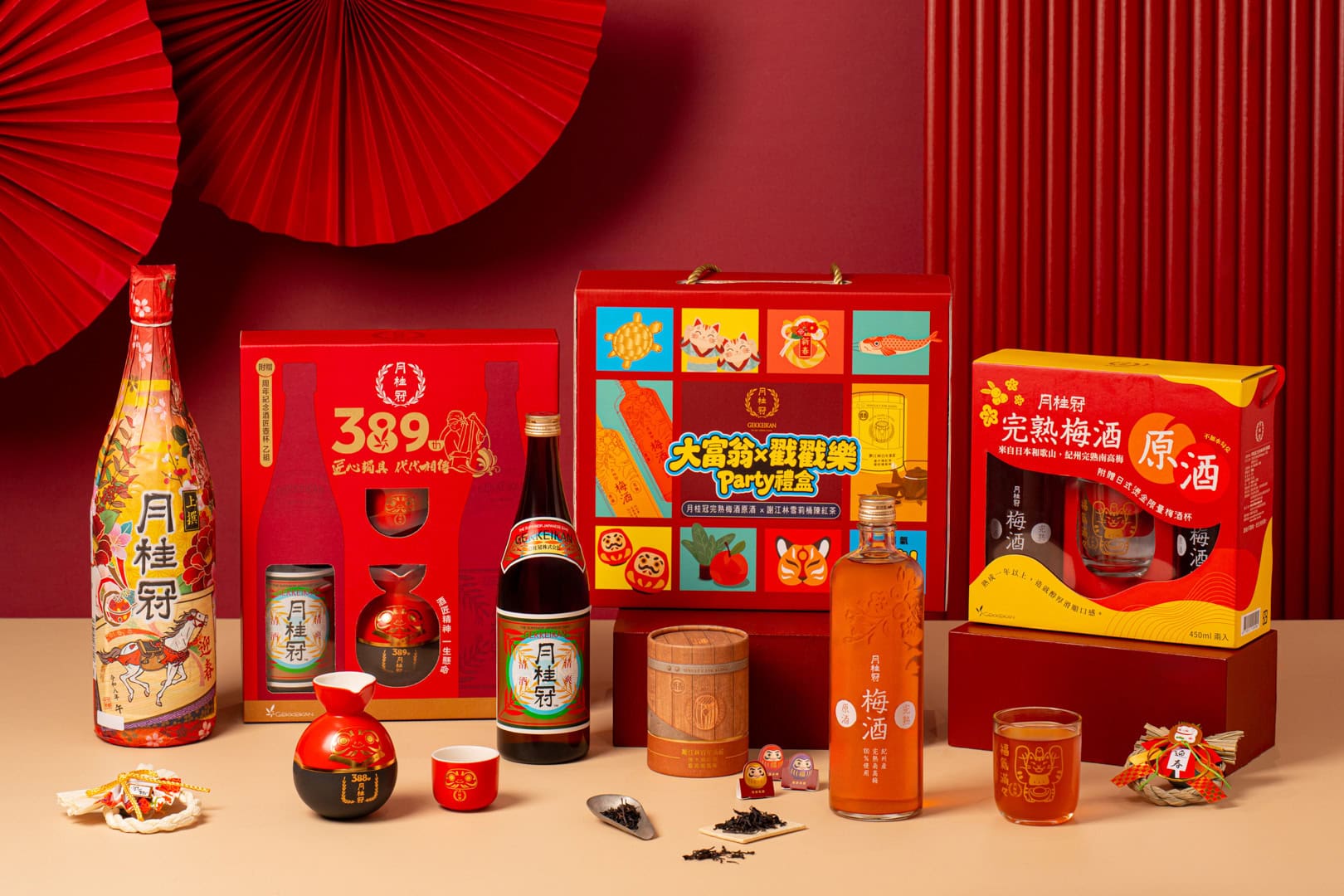 月桂冠389周年新年禮盒以紅金配色展示多款酒品、茶葉與陶瓷器皿，搭配傳統扇形裝飾，溫暖燈光營造喜慶氛圍，台中市奇力克影像工作室KYRIC STUDIO執行品牌形象攝影。