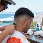 Dégradé espagnol court low mid skin fade, coiffeur règle la tondeuse sur la nuque
