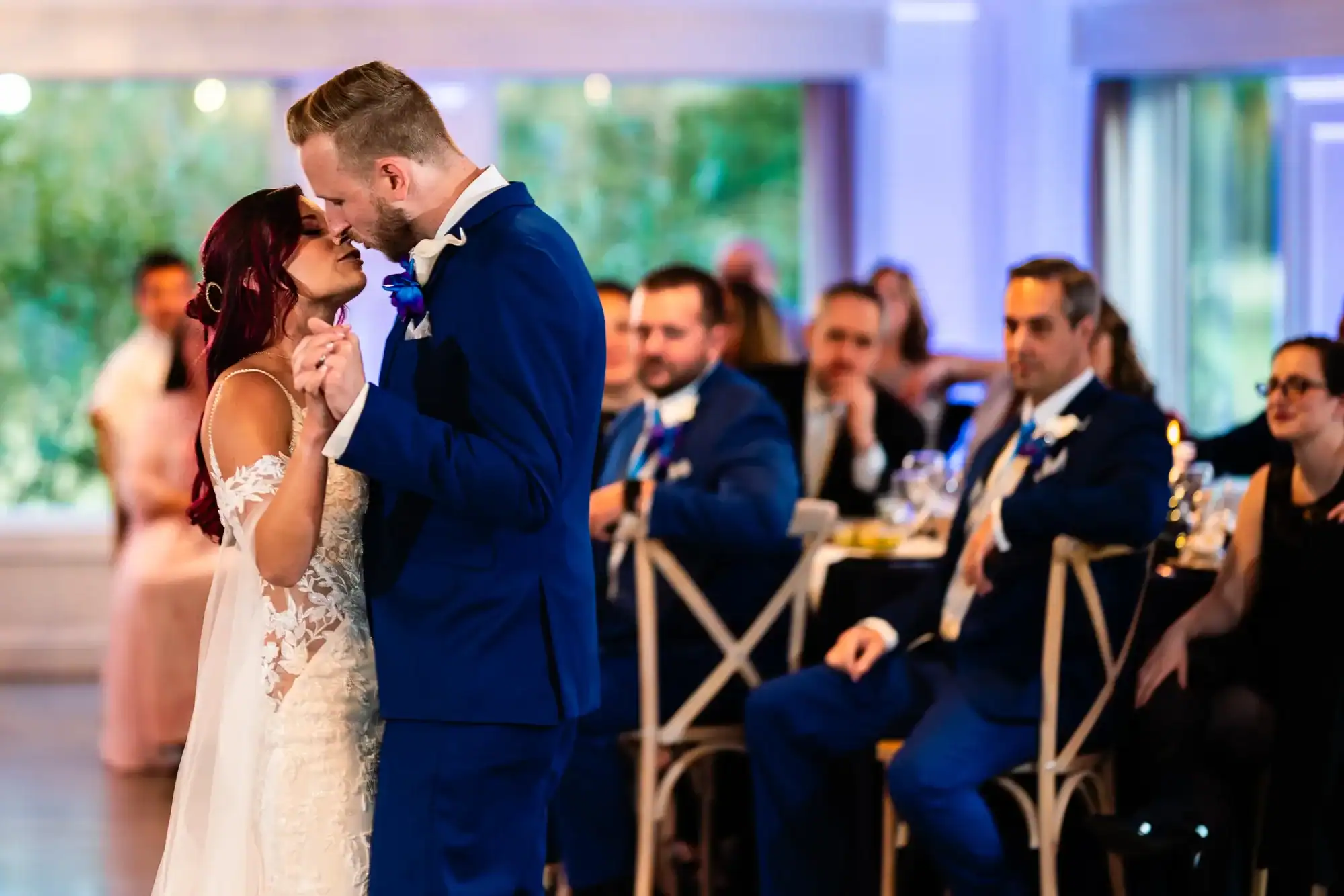A bride and groom share their first dance, surrounded by seated guests in a warmly lit reception hall taken by a Connecticut wedding photographer