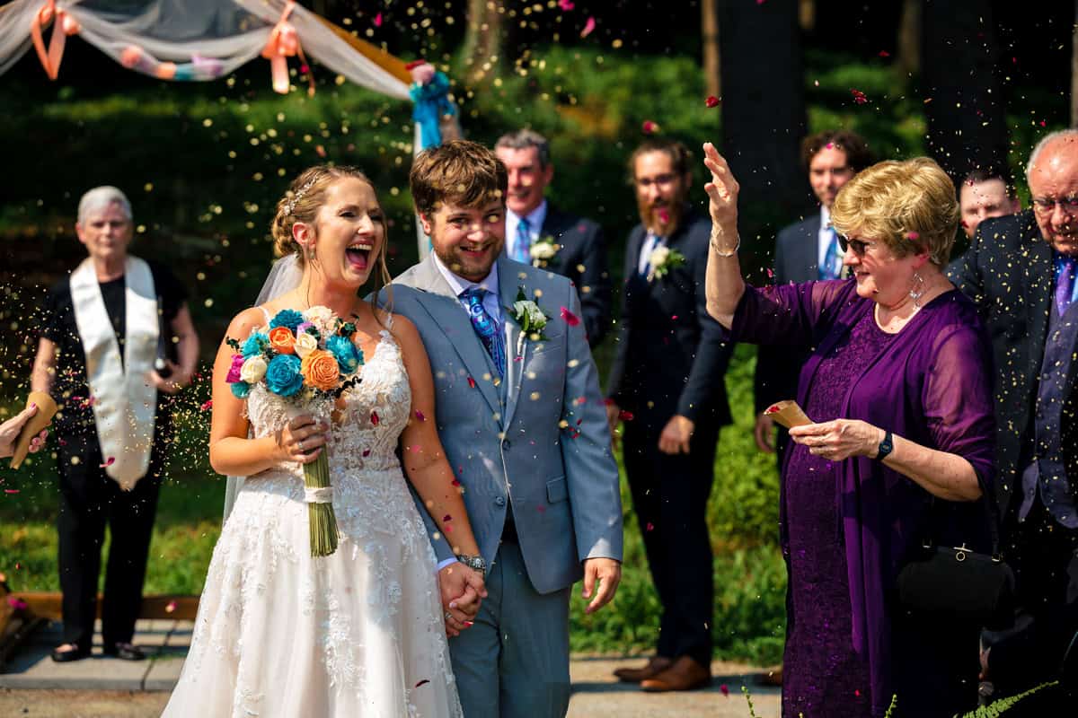Bride and groom celebrating with guests throwing confetti during joyful Hartford County wedding ceremony photographed by Ladman Studios