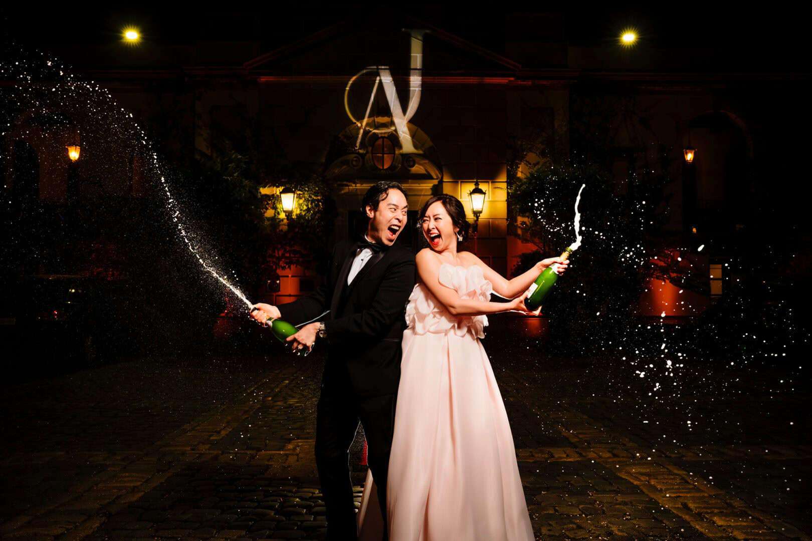 Couple spraying champagne during nighttime wedding celebration in fairfield County