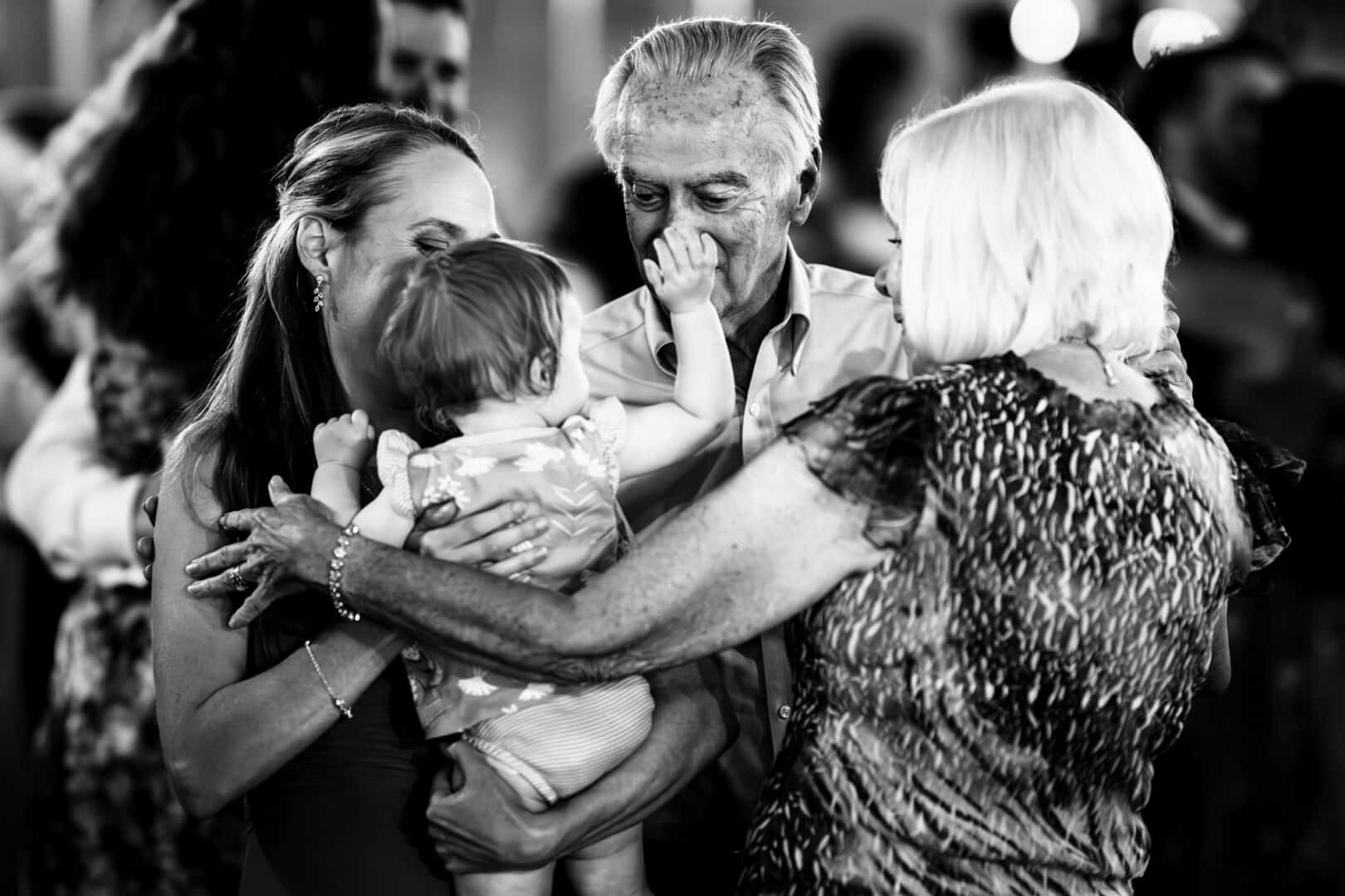 Emotional candid photo of grandparents hugging bride and baby during fairfield County wedding reception