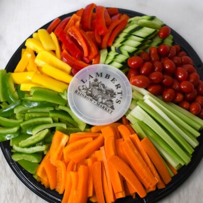 Colorful fresh vegetable platter with cherry tomatoes, cucumbers, bell peppers, carrots, and celery.