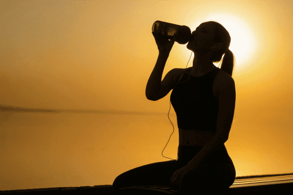 A woman drinking protein in the sunset