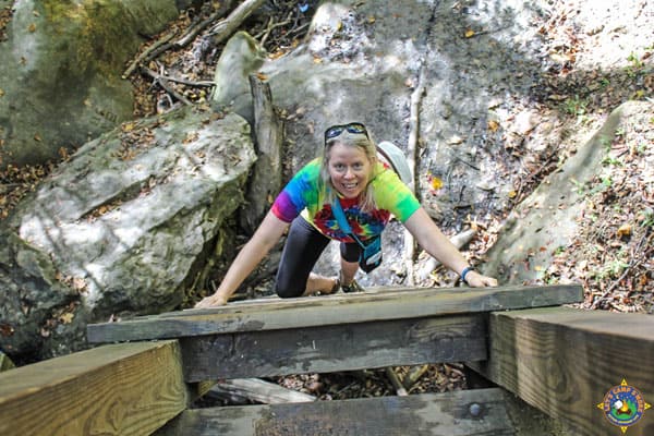 smiling woman climbing a hiking ladder 