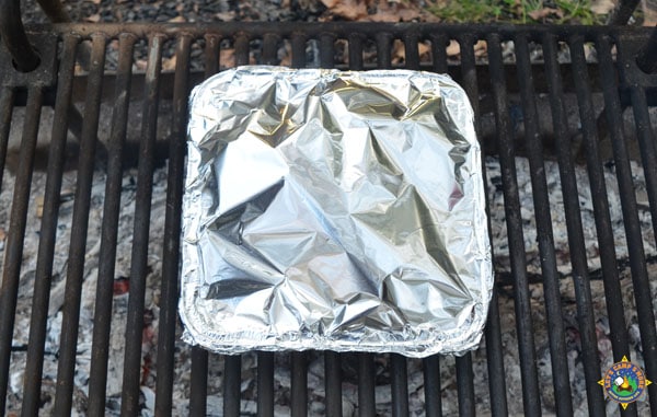 foil pan on a grate over a campfire
