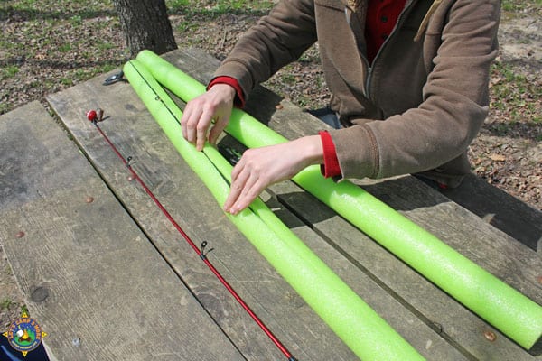 person putting a fishing pole into a cut pool noodle