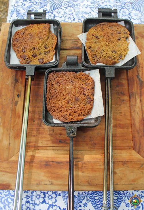 3 chocolate chip cookies that were baked over the campfire shown in pie irons
