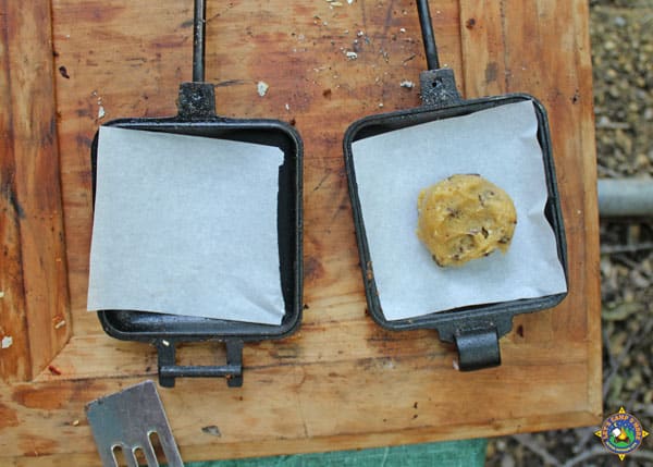 a scoop of cookie dough on parchment paper on one half of a pie iron