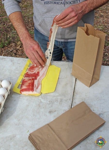 Bacon in a Breakfast in a Bag man pulling a piece off a package of bacon