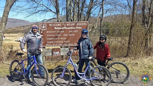 Whitetop Station Virginia Creeper Trail family posing with bicycles in front of the Mount Rogers sign