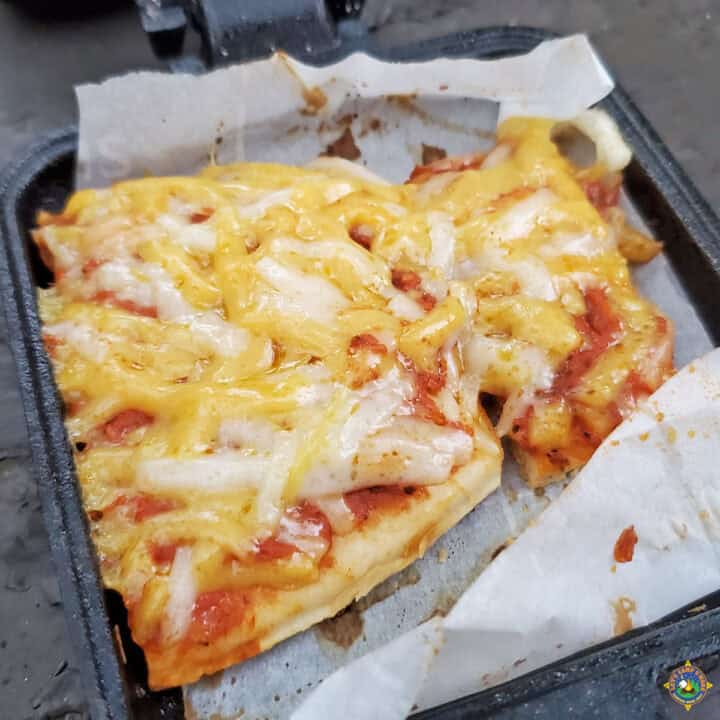 close up of a piece of pie iron pizza made over the campfire while camping